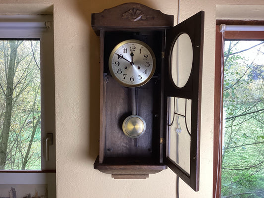 Holzregulator aus der Zeit um 1930 mit geöffneter verglaster Tür, Werk und Pendel sichtbar