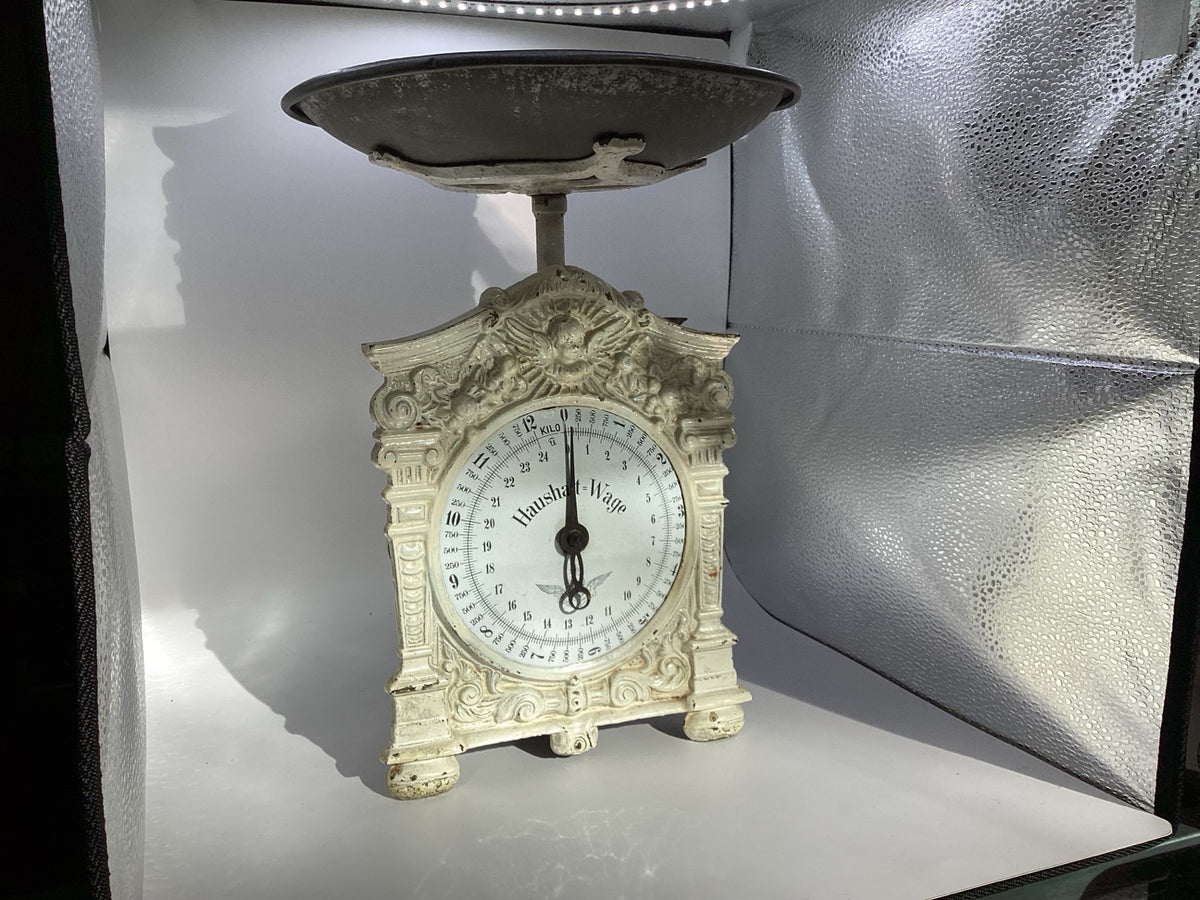 Alte mechanische Haushalt-Wage mit cremeweißem Ziergehäuse und dunkler Waagschale, Gesamtansicht