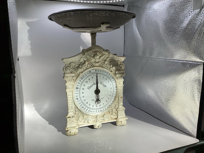 Alte mechanische Haushalt-Wage mit cremeweißem Ziergehäuse und dunkler Waagschale, Gesamtansicht